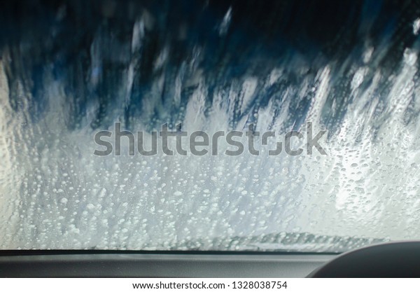 Automatic car wash. View from inside a car being\
washed at a car wash from the driver seat. Auto inside carwash from\
interior. Car windshield cleaning. Automatic conveyorized tunnel\
vehicle wash.