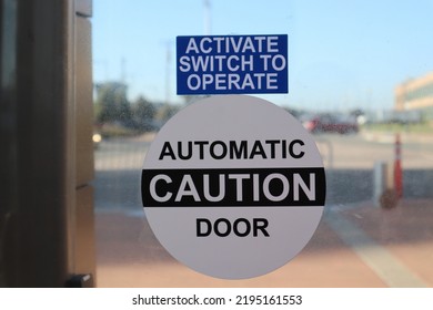 Automatic Caution Door Sign. Close Up. Photo Of The Sign On Dirty Glass Door. 