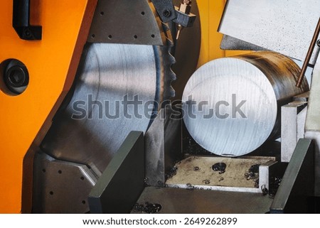 automatic circular saw cutting large metal part with round cross-section, industrial concept background.