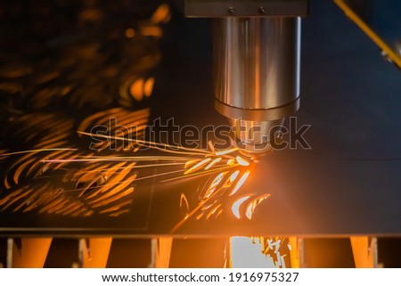 Automatic cnc laser cutting machine working with sheet metal with sparks at factory, plant. Dark background. Metalworking, machining, industrial, equipment, technology, manufacturing concept
