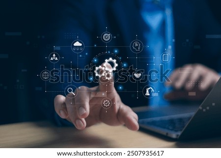 Automatic control system with modern technology for managing business processes Concept. A businessman taps a gear icon showing the operation of robot automation software on computer.