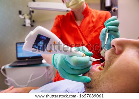 Automatic Digital Periodontitis detector being used on patients teeth for diagnosing periodontal status and diseases  Digital dentistry, modern techology, oral hygiene.
