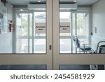 Automatic doors seen at the exit of an NHS outpatients department in a busy British hospital. Ports wheelchairs can be seen in the lobby area for immobile outpatients.