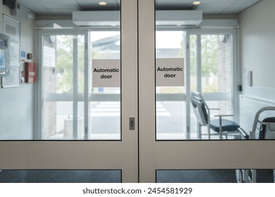 Automatic doors seen at the exit of an NHS outpatients department in a busy British hospital. Ports wheelchairs can be seen in the lobby area for immobile outpatients. - Powered by Shutterstock