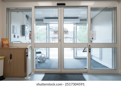 Automatic doors seen at the exit of an NHS outpatients department in a busy British hospital. The building  seen through the doors is an A and E department.