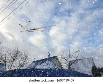automatic drone piloted remotely by radio control patrols country village covered with falling snow