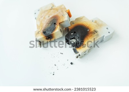 Automatic electrical switch damaged by short circuit, ash on background, isolated on white background. Selective focus, noise. Fire hazard
