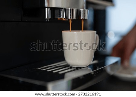 Automatic espresso machine dispensing hot, fresh coffee into a white ceramic cup. Preparing a morning caffeine drink