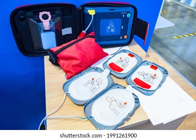 Automatic external defibrillator. Portable defibrillator on a wooden table. Defibrillator for medical care. Device for provision of emergency medical care. Automatic cardioverter with nursing manual - Shutterstock ID 1991261900