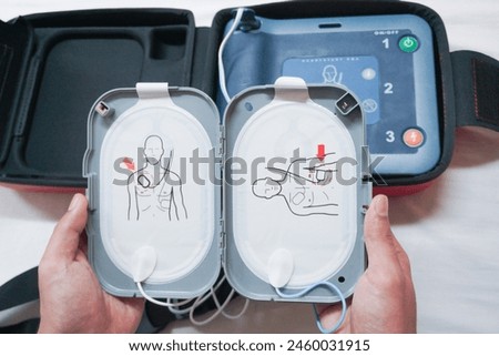  Automatic external defibrillator. Portable defibrillator on a wooden table. Defibrillator for medical care. Device for provision of emergency medical care. Automatic cardioverter with nursing manual