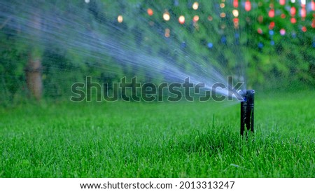 Automatic garden irrigation system watering lawn. Savings of water from sprinkler irrigation system with adjustable head. Automation for lawn irrigation, gardening, soccer fields or golf courses.