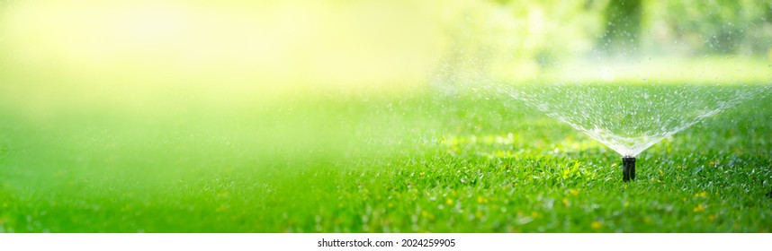 Automatic garden lawn sprinkler in action watering grass using as background cover page - Shutterstock ID 2024259905