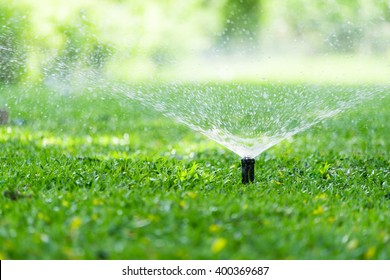 Automatic Garden Lawn sprinkler in action watering grass.