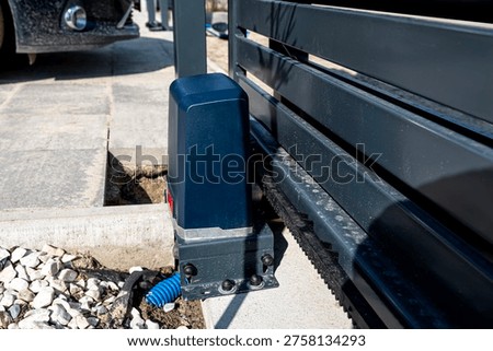 Automatic gate motor installing on a concrete base, showing the drive gear and gate rack