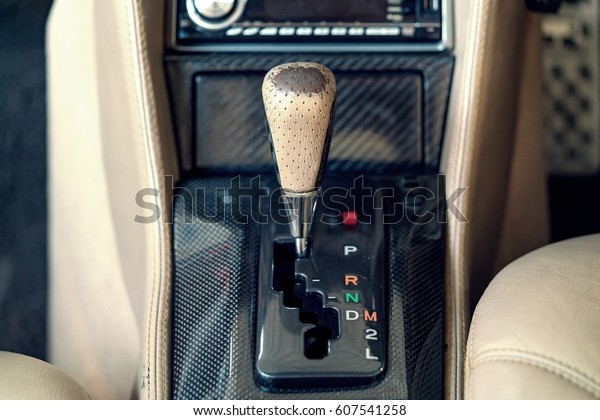 Automatic gear shift handle on carbon fiber panel in\
modern car.