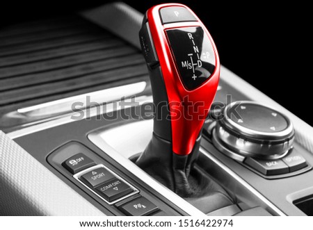 Automatic gear stick of a modern car. Modern car interior details. Close up view. Car detailing. Automatic transmission lever shift. Black leather interior with red stitching. 
