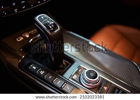 Automatic gear stick of a modern car, multimedia and navigation control buttons. Car interior details. Transmission shift. Shallow dof