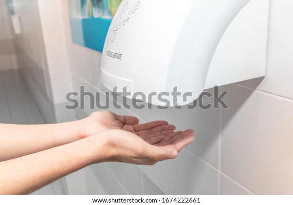 Automatic
hand dryer in public toilet or restroom hygiene concept. A man
hands using utomatic hand dryer in
bathroom.