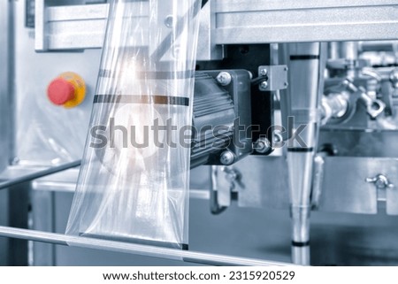 Automatic industrial machine for plastic packaging with light effect of products and food. automated packaging line with plastic film in a light blue scene. product packaging concept