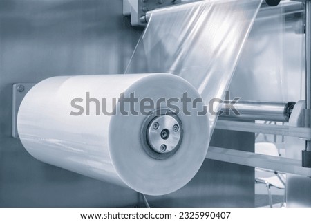 Automatic industrial machine for plastic packaging with light effect of products and food. shaft of an automated packaging line with plastic film in a light blue scene. product packaging concept