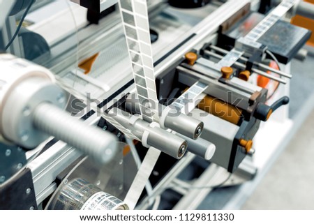 Automatic labeling machine. The labeled tape is located between the feed rollers.