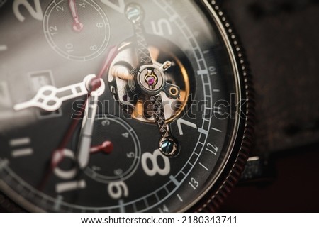 Automatic mechanical wrist watch with black clock face and open balance, close-up photo with selective focus