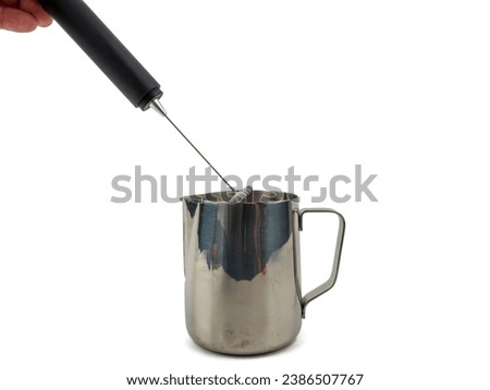 Automatic milk foam maker. Metal milk mug and electric milk frother isolated on a white background.