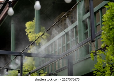 Automatic mist nozzle water spraying system to make humidifier and cooling climate to reduce hot weather. Water fog machine working during hot summer day. Refreshes plant and cleaning air outdoors - Shutterstock ID 2167578675