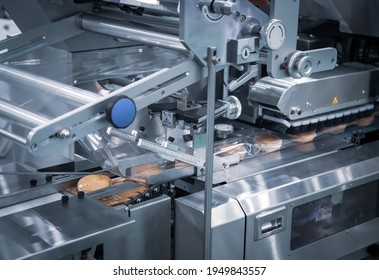 Automatic packing of bakery product flow pillow packing machine. Bread, toast, bun plastic wrapping machine on bakery production line