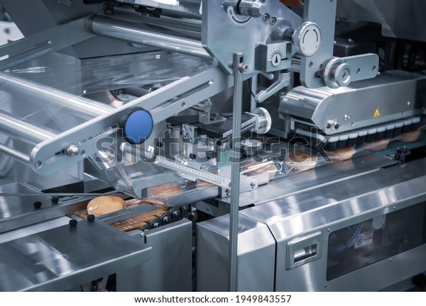 Automatic packing of bakery product flow pillow\
packing machine. Bread, toast, bun plastic wrapping machine on\
bakery production\
line