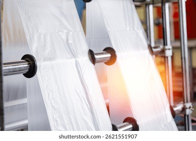 Automatic polyethylene plastic bag production, sunlight. Closeup roller of industry machine for packaging.
