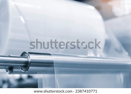 Automatic polyethylene plastic bag production machine with lighting effect. Close-up of the roller of the plastic bag production machine in the light blue scene. product packaging concept