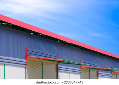Automatic roller shutter doors with awning of modern rental warehouse building against blue sky background, perspective side view