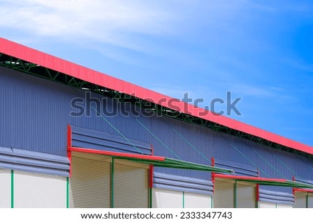 Automatic roller shutter doors with awning of modern rental warehouse building against blue sky background, perspective side view