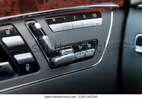 Automatic seat memory\
buttons with white signs and symbols located diagonally from top to\
bottom on a grey modern car control panel with brown and\
chrome-plated metal\
elements.