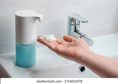 Automatic soap dispenser in the bathroom. Hand with soapy solution closeup - Powered by Shutterstock
