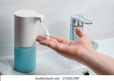 Automatic Soap Dispenser In The Bathroom. Hand With Soapy Solution Closeup