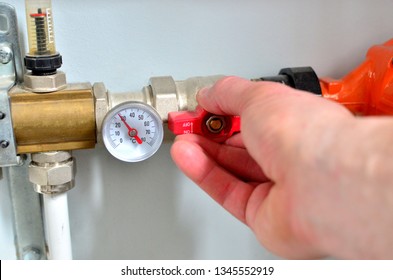 Automatic Water Supply System, Hands Turn Off The Main Valve. Close Up Of Manometer, Pipe, Flow Meter, Water Pumps And Valves Of Heating System In A Boiler Room At Home