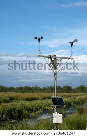 Automatic weather station with solar panel in a green marshland environment