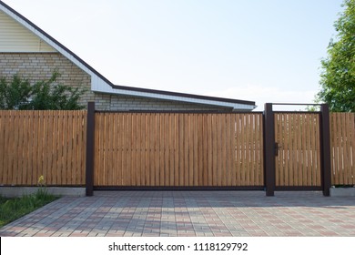 Automatic wooden gate in a private house, on a sunny day.