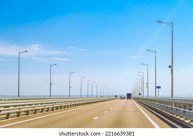 Automobile bridge across the Kerch Strait or Crimean bridge. Asphalt road with marking and road lampposts with alarm annunciators. 151 km rosautodor on road sign (translation from Russian).