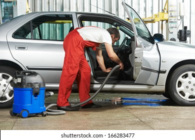 Automobile Cleaning Theme. Mechanic Hoovering The Car Cabin With Vacuum Cleaner At Auto Repair Shop Garage