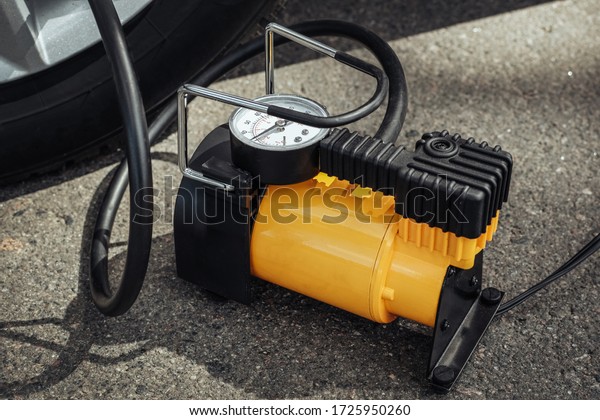 Automobile compressor. Electric pump inflates a\
car wheel close-up