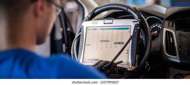 Automobile Computer Diagnosis. Car Mechanic Repairer Looks For Engine Failure On Diagnostics Equipment In Vehicle Service Workshop