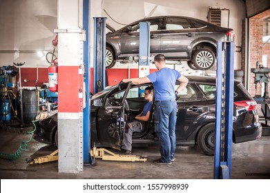 Automobile Computer Diagnosis. Car Mechanic Repairer Looks For Engine Failure On Diagnostics Equipment In Vehicle Service Workshop