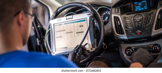 Automobile Computer Diagnosis. Car Mechanic Repairer Looks For Engine Failure On Diagnostics Equipment In Vehicle Service Workshop