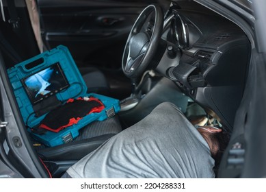 Automobile Computer Diagnosis. Car Mechanic Repairer Looks For Engine Failure On Diagnostics Equipment In Vehicle Service Workshop