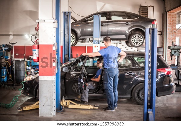 Automobile computer diagnosis. Car mechanic\
repairer looks for engine failure on diagnostics equipment in\
vehicle service\
workshop