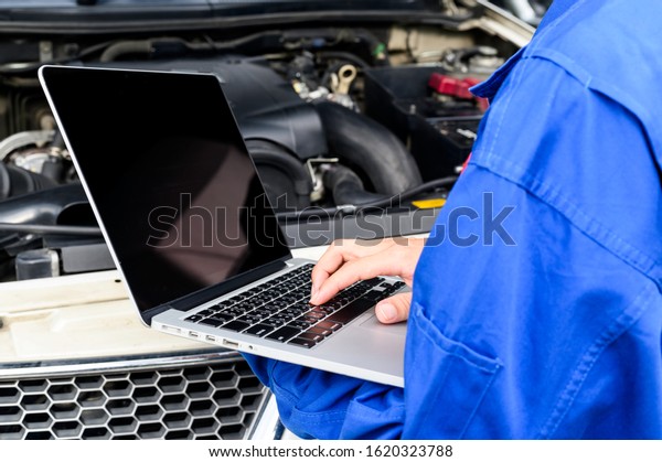 Automobile computer diagnosis. Car mechanic\
repairer looks for engine failure on diagnostics equipment in\
vehicle service\
workshop.