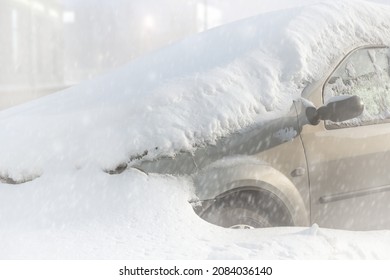 Automobile is covered with snow. Trapped in a snowdrift in a heavy snowfall. Bad winter weather on the roads. Blizzard. Abandoned car in the cold.